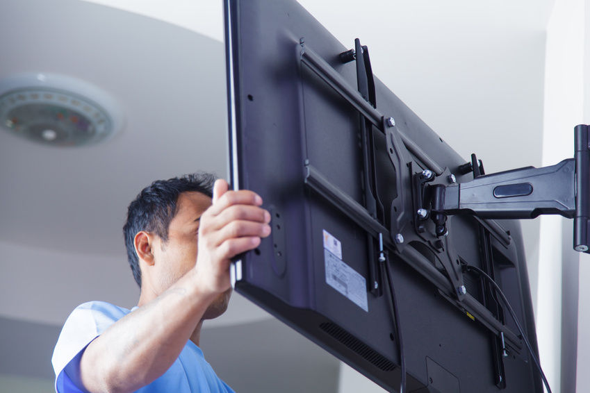 Man moving a TV which is attached to a wall bracket